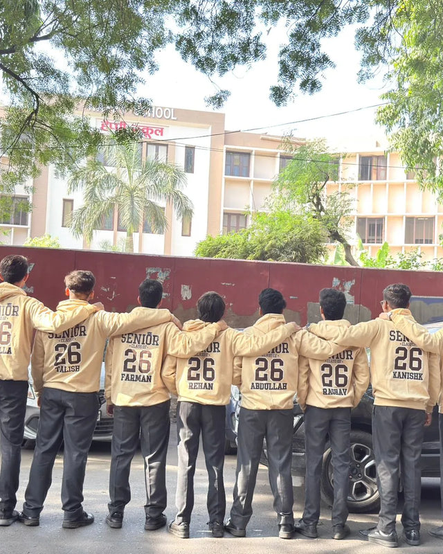 Senior batch '26 students in sand hoodies with names printed on the back